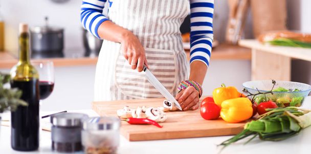 Young woman cutting vegetables in kitchen - Fotó, kép