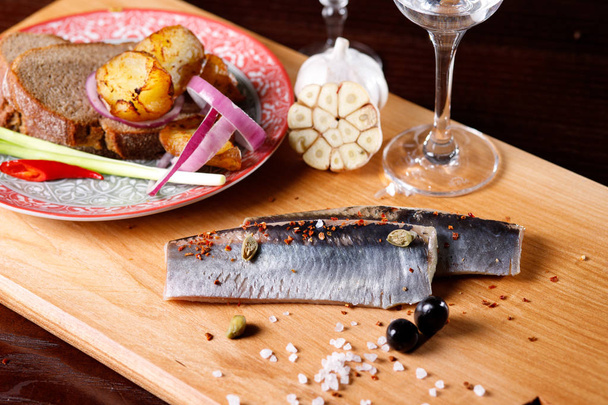 Marinated herring fillet with sliced onions,potatoes, garlic and a glass of vodka. - Valokuva, kuva