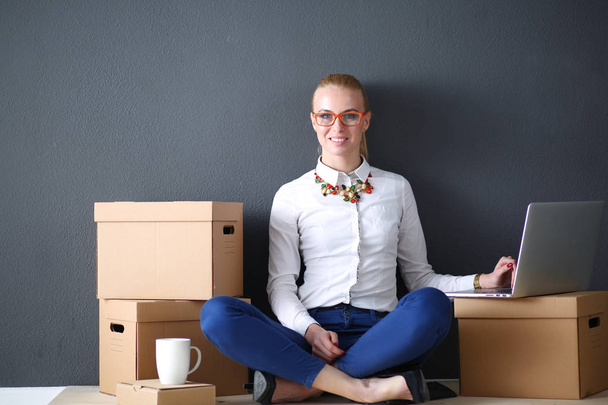 Woman sitting on the floor near a boxes with laptop . Businesswoman - Φωτογραφία, εικόνα