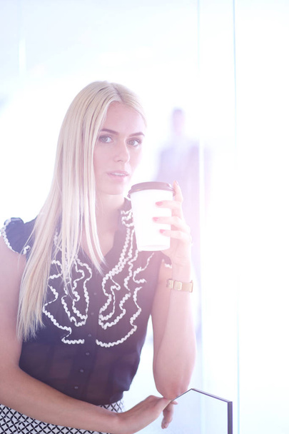 Businesswoman holding a cup of coffee standing in office . - Foto, Bild