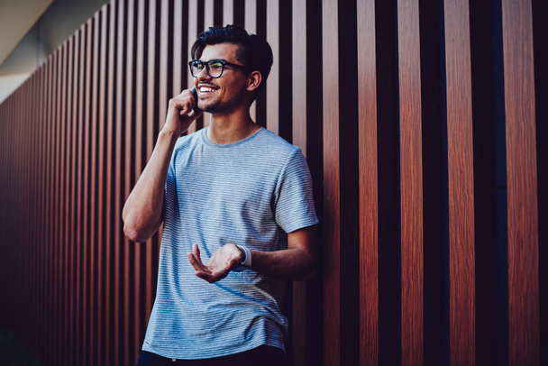 Emotional handsome hipster guy in eyewear discussing ideas during mobile conversation. - 写真・画像