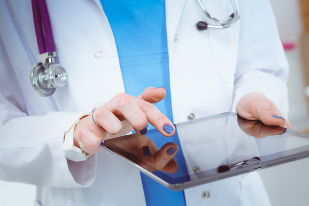 Médica usando um comprimido digital e de pé sobre fundo branco. Mulheres médicas. - Foto, Imagem