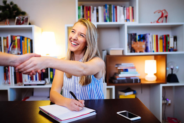 smiling young woman shaking hands in her office - Valokuva, kuva