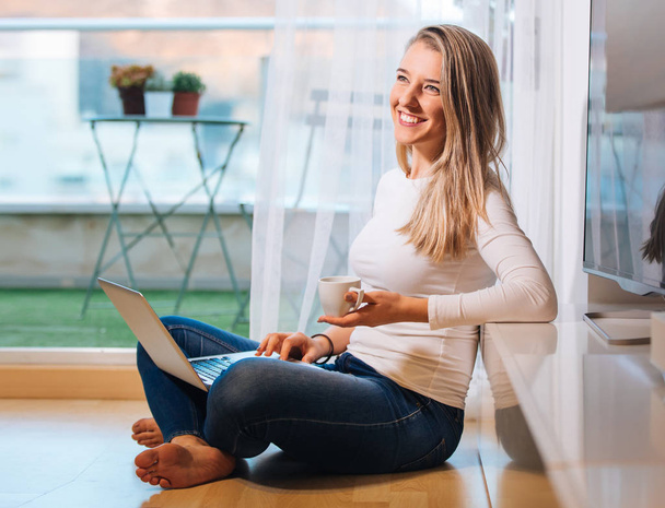 relaxed smiling barefoot woman sitting on the floor looking at h - Photo, image
