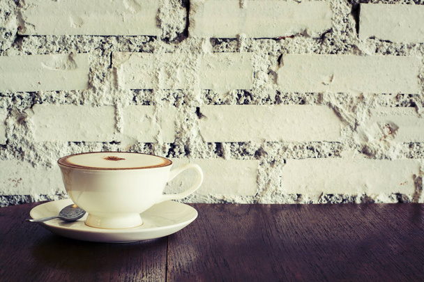 Kahvikuppi Espresso puupöydällä tiiliseinä tausta
 - Valokuva, kuva