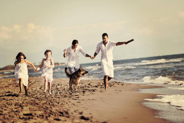 happy young family in white clothing have fun and play with beautiful dog at vacations on beautiful beach  - Φωτογραφία, εικόνα