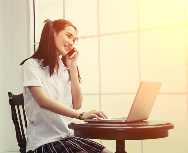 Iskolai nő használ laptop tanulmányi és beszélő telefon t ül - Fotó, kép