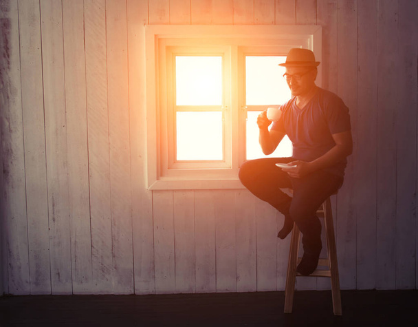 yakışıklı adam w üzerinde oturan pencere yakınındaki kahve veya çay içme - Fotoğraf, Görsel