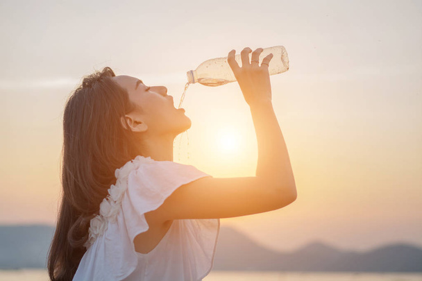 Όμορφη γυναίκα στέκεται πόσιμο νερό από το μπουκάλι στο μ - Φωτογραφία, εικόνα