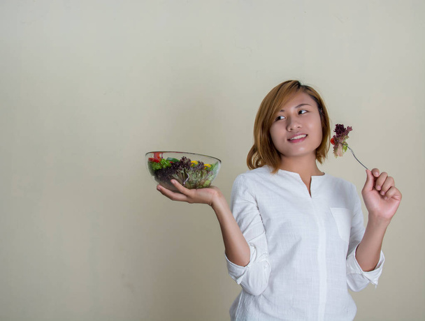 красива жінка, що стоїть тримає чашу салату, їсть трохи овочів
 - Фото, зображення