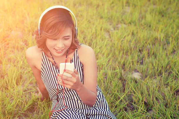 Beautiful sexy woman sitting  listening music from headphone smi - Foto, afbeelding