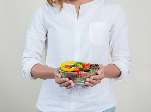 Close-up of womans hands holding bowl with fresh salad - Foto, Bild
