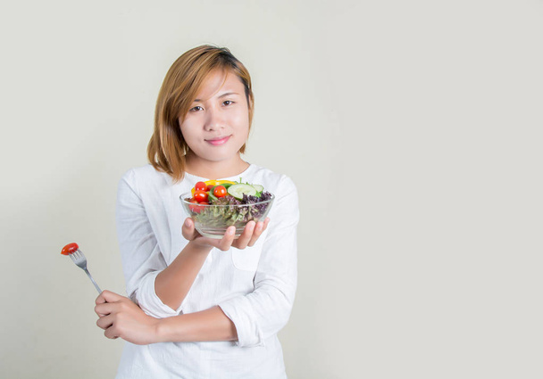 Mooie jongedame met plantaardige slakom en vork in hand - Foto, afbeelding