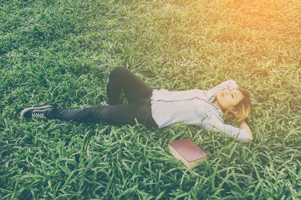 Young hipster woman lying down on grass when she tired after rea - Фото, зображення