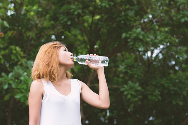 Young beautiful woman holding water at green park. - Foto, Bild