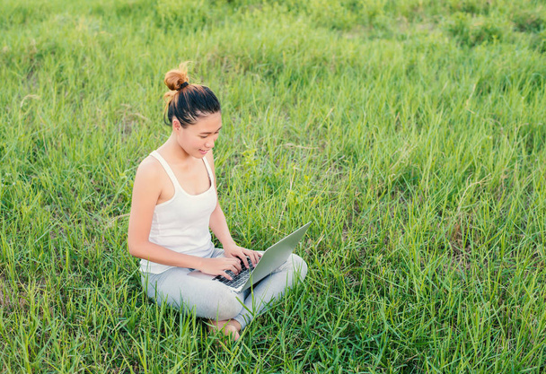 Young beautiful asian woman using Laptop on nature meadows. - 写真・画像