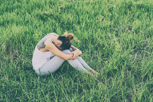 Concepto de vida de la mujer: mujer triste abrazar su rodilla y llorar en los prados
. - Foto, imagen
