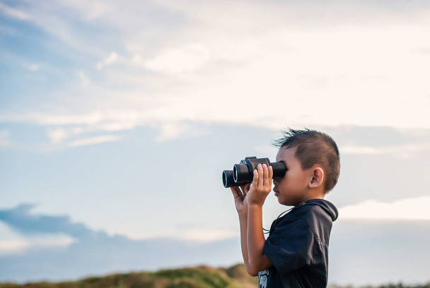 Happy kid playing binoculars in the meadows. - Photo, image