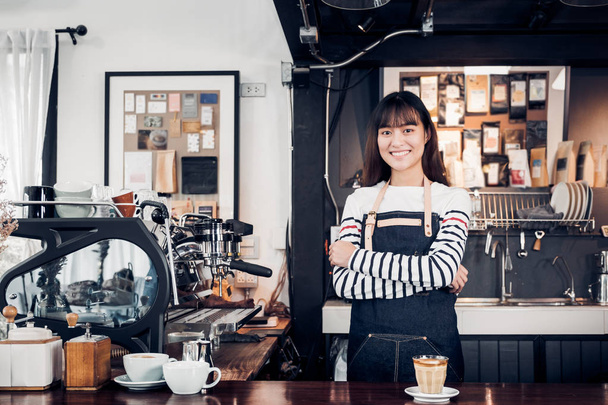 asiatique femelle barista porter jean tablier croisé son bras au comptoir
 - Photo, image