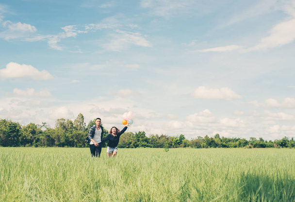 junges Paar rennt und hält Ballon im grünen Gras belo - Foto, Bild