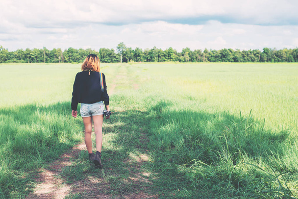 Спина молодой женщины с ретро-камерой на травяном поле
 - Фото, изображение