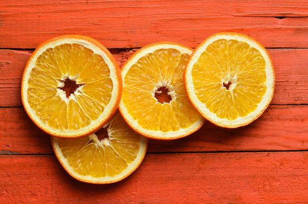 Сушені апельсинові скибочки на оранжевому дерев'яному фоні. Вид зверху
. - Фото, зображення