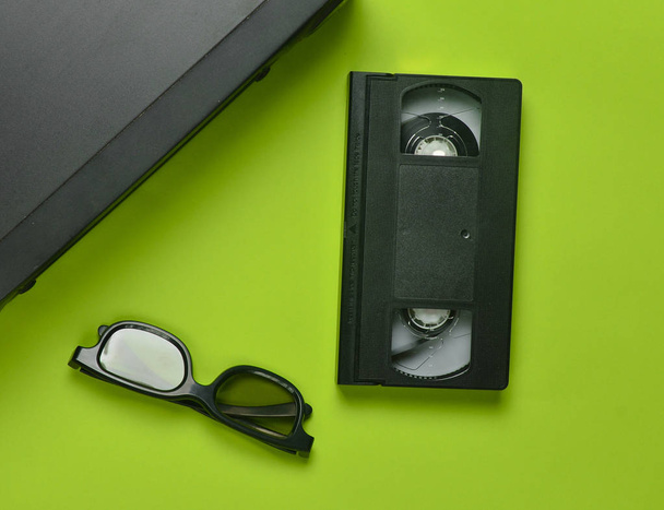 Odtwarzacz VHS, kaset wideo, 3d okulary na zielonym tle. Przestarzałe technologie mediowe. Widok z góry. - Zdjęcie, obraz