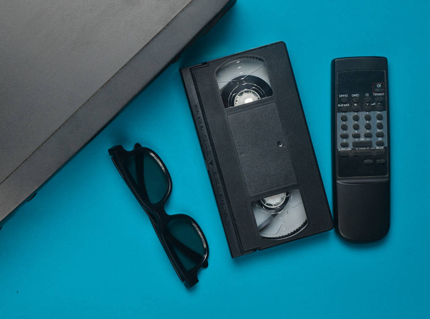 VHS player, κασέτες βίντεο, 3d γυαλιά, τηλεκοντρόλ, σε γαλάζιο φόντο. Απαρχαιωμένες τεχνολογίες πολυμέσων. Το Top view. - Φωτογραφία, εικόνα