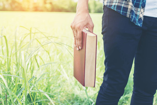 Man hands holding books on green meadow. - Photo, Image