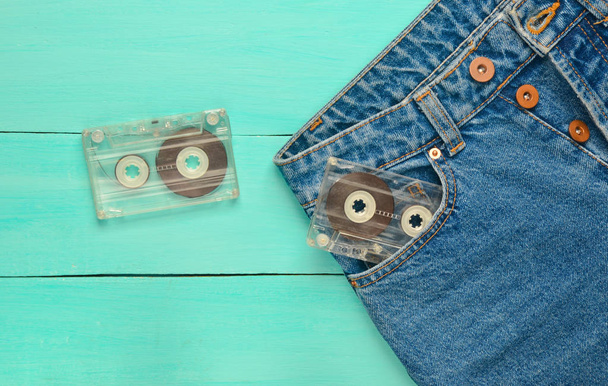 Two audio cassettes in a jeans pocket on a blue wooden surface. Media technology from the 80s. - Photo, Image