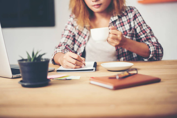 Деловая женщина держит чашку кофе и пишет бизнес-план
 - Фото, изображение