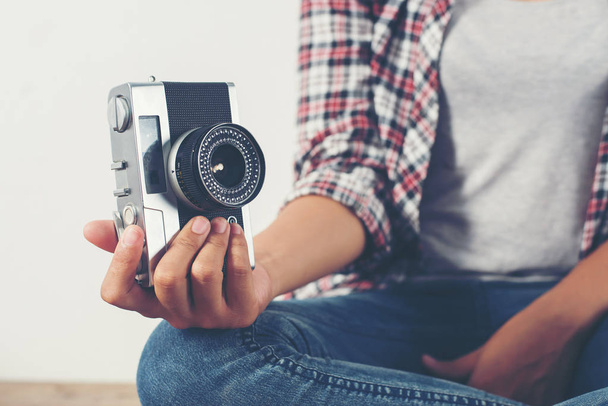 Νέοι hipster φωτογράφος χέρι κρατά κάμερας ρετρό κάθεται στο  - Φωτογραφία, εικόνα