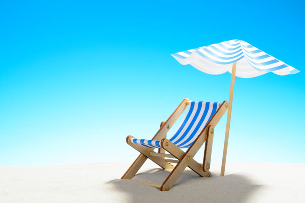Una chaise longue bajo un paraguas en la playa de arena, cielo con espacio para copiar
 - Foto, imagen