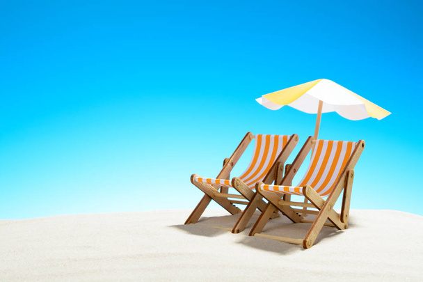 Dois chaise longue sob um guarda-chuva na praia de areia, céu com espaço de cópia
 - Foto, Imagem