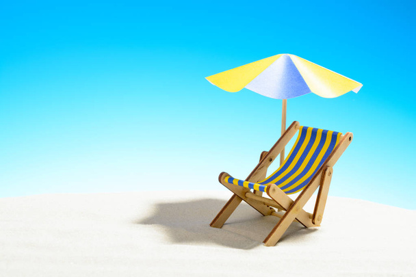 eine Chaiselongue unter einem Sonnenschirm am Sandstrand, Himmel mit Kopierraum - Foto, Bild