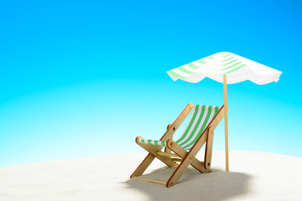 Una chaise longue bajo un paraguas en la playa de arena, cielo con espacio para copiar
 - Foto, imagen