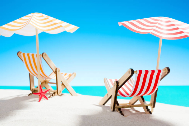 zwei Liegestühle unter einem Sonnenschirm am Sandstrand am Meer und am Himmel mit Kopierraum - Foto, Bild