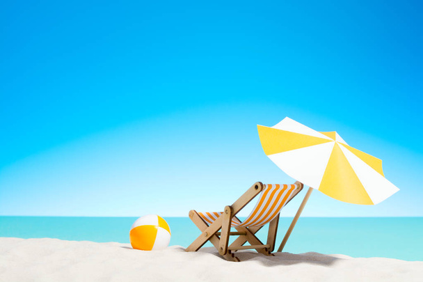 Liegestuhl mit Sonnenschirm und Strandball an der Küste - Foto, Bild