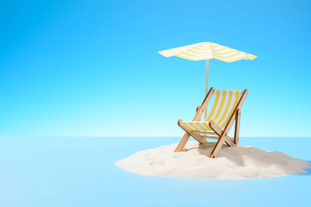 El concepto de unas vacaciones tropicales. Una chaise longue bajo un paraguas en la isla de arena. Cielo con espacio de copia
 - Foto, imagen