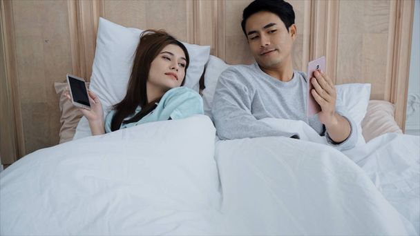 The young married couple used smartphone chatting on bed - Φωτογραφία, εικόνα