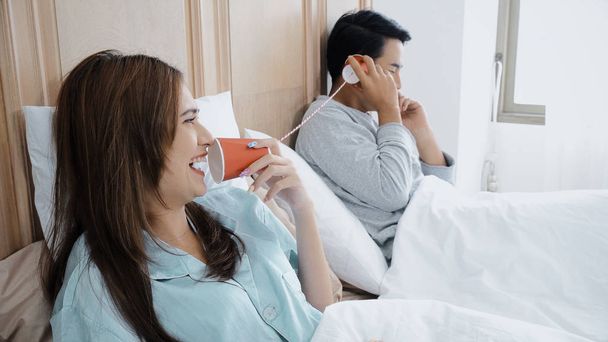 Young married couple playing with can phone to talking together - Photo, Image
