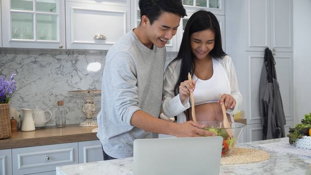 The couple are cooking together happily with laptop computer - 写真・画像
