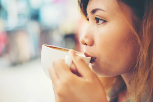 Fiatal gyönyörű nő forró cappuccino kávét inni kávézó. - Fotó, kép
