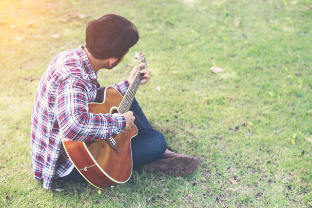 Молодий хіпстер практикував гітару в парку, щасливий і насолоджуватися р
 - Фото, зображення