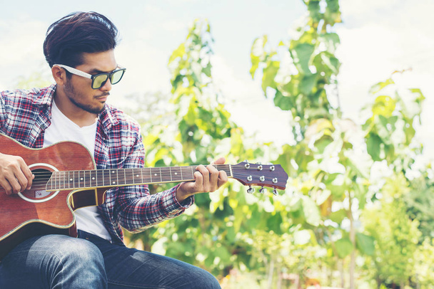 流行に敏感な若い男性の肖像画幸せな公園でギターを練習 - 写真・画像