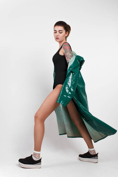 portrait of young fashion woman with tattoo on hand in green raincoat - Photo, Image