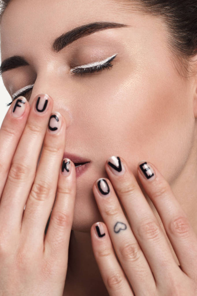 portrait de jeune femme de mode avec maquillage et texte sur les ongles
 - Photo, image