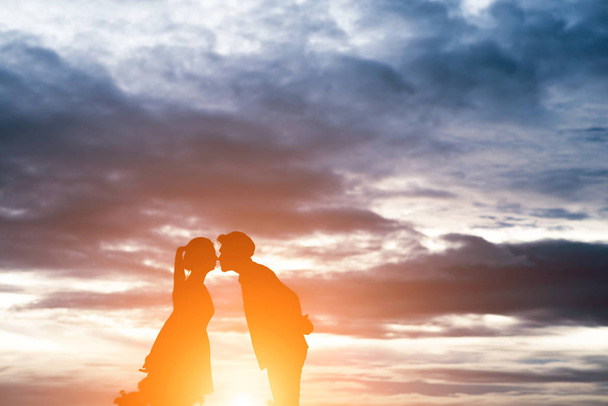 Silhouette of sweet couple kissing over sunset background. - 写真・画像