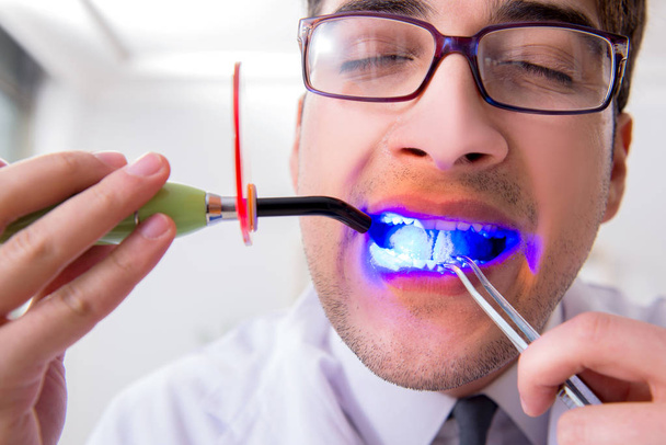 Divertido dentista con luz de curado en concepto médico - Foto, imagen