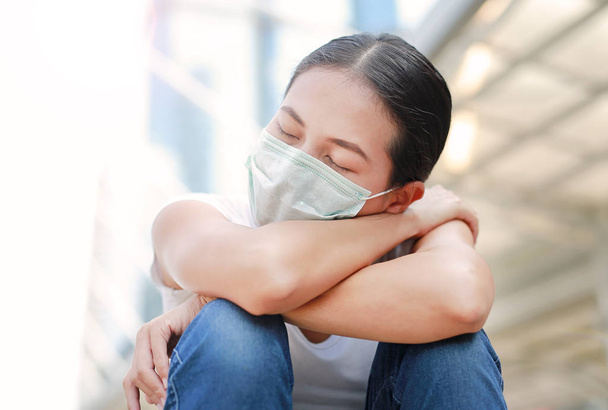 Woman wearing protective mask to protect pollution and the flu sitting at public area. - Photo, Image